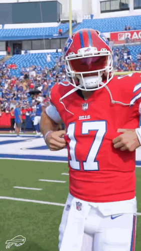 A Football Player Is Standing On A Field Wearing A Red Jersey And A Helmet . GIF