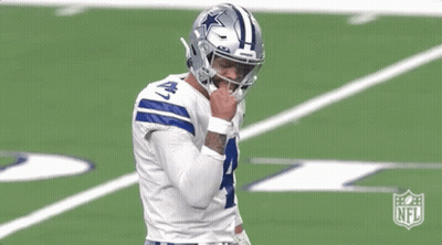 A Football Player Is Standing On A Field With His Hand On His Face . GIF