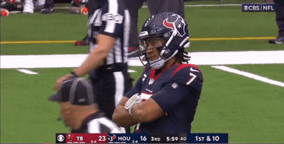 A Football Player Is Standing On The Field With His Arms Crossed And A Referee Standing Behind Him . GIF