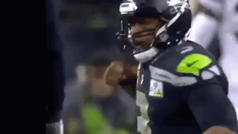 A Football Player Is Wearing A Helmet And Giving A Thumbs Up During A Game . GIF