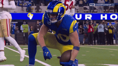 A Football Player Kneeling On The Field With A Fox Championship Logo Behind Him GIF