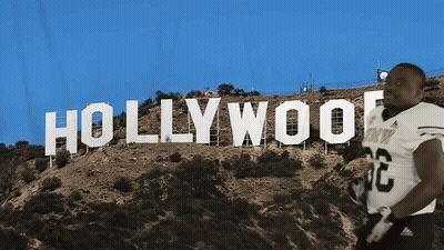 A Football Player Stands In Front Of A Hollywood Sign GIF