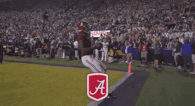 A Football Player Stands In Front Of A Touchdown Banner GIF