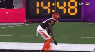 A Football Player Stands On The Field In Front Of A Digital Scoreboard That Says 14:48 GIF
