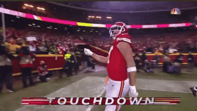 A Football Player Stands On The Field With The Words Touchdown In The Corner GIF