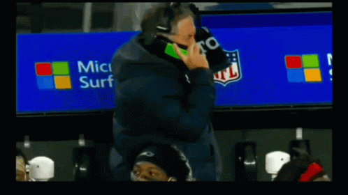 A Football Player Talking On A Cell Phone With A Microsoft Surface Advertisement Behind Him GIF