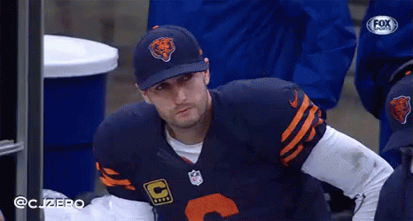 A Football Player Wearing A Bears Hat Is Sitting On The Sidelines GIF