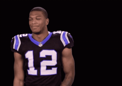 A Football Player Wearing A Black And Blue Jersey With The Number 12 On It GIF