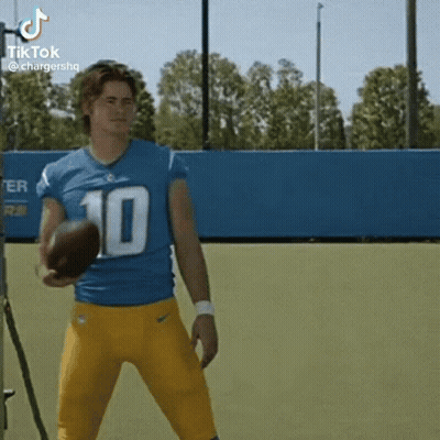 A Football Player Wearing A Blue And Yellow Uniform Is Holding A Football . GIF