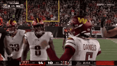 A Football Player Wearing A Daniels Jersey Is Standing On The Field With His Teammates GIF
