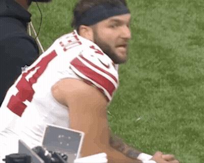 A Football Player Wearing A Headband Is Sitting On The Sidelines . GIF