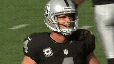 A Football Player Wearing A Helmet And A Black Jersey Is Standing On The Field . GIF