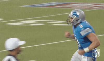 A Football Player Wearing A Helmet And A Blue Shirt Is Running On A Field . GIF