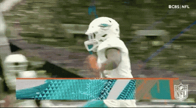 A Football Player Wearing A Helmet And A Dolphins Jersey Is Standing On A Field . GIF