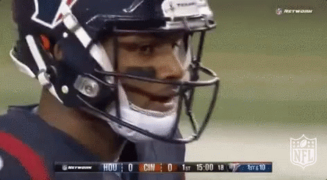 A Football Player Wearing A Helmet And A Mask Is Standing On A Field . GIF