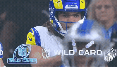 A Football Player Wearing A Helmet And A Rams Jersey Is Standing In Front Of A Crowd . GIF