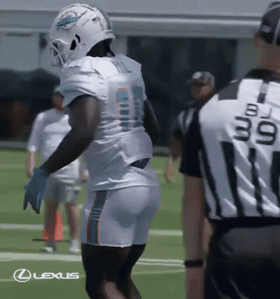 A Football Player Wearing A Helmet And Shorts Is Standing On A Field With A Referee . GIF