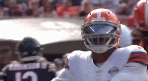 A Football Player Wearing A Helmet And Sunglasses Is Standing On A Field . GIF