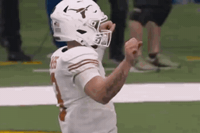 A Football Player Wearing A Helmet Is Celebrating A Touchdown On The Field . GIF