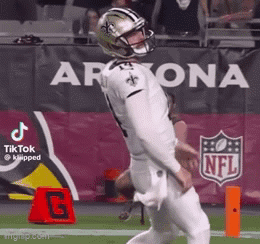 A Football Player Wearing A Helmet Is Kicking A Ball On The Field . GIF