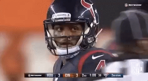 A Football Player Wearing A Helmet Is Standing On A Field . GIF