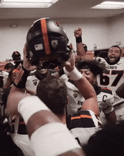 A Football Player Wearing A Jersey That Says Beavs Is Holding Up His Helmet GIF