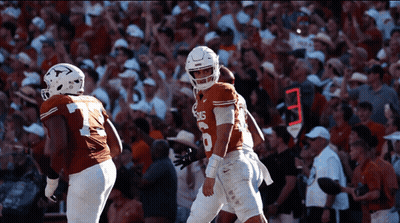 A Football Player Wearing A Jersey That Says Texas Stands In Front Of A Crowd GIF