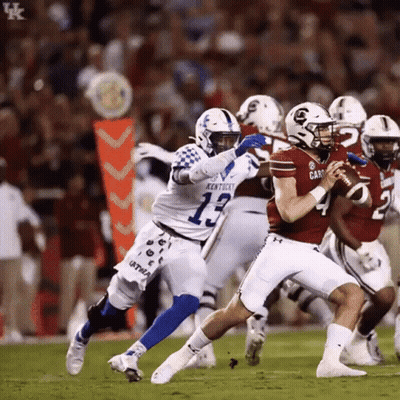A Football Player Wearing A Kentucky Jersey Is Trying To Tackle Another Player GIF