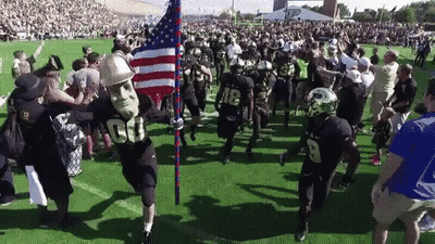A Football Player Wearing A Mask With The Number 00 On It Is Holding An American Flag GIF