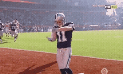 A Football Player Wearing A Number 11 Jersey Is Dancing On The Field . GIF