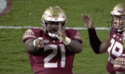 A Football Player Wearing A Number 21 Jersey Is Pointing At The Camera . GIF