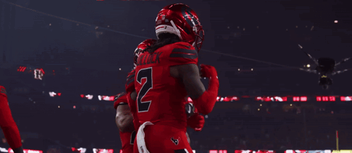 A Football Player Wearing A Number 7 Jersey Stands In A Huddle With His Teammates GIF