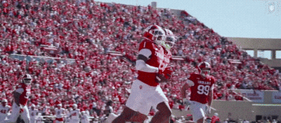 A Football Player Wearing A Number 99 Jersey Runs With The Ball GIF
