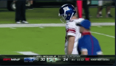 A Football Player Wearing A Ny Giants Helmet Talks To A Referee On The Field GIF