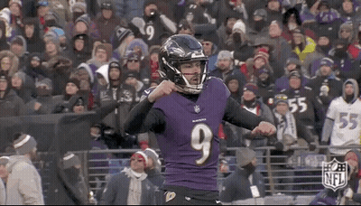A Football Player Wearing A Purple Jersey And A Black Helmet Is Standing In Front Of A Crowd . GIF