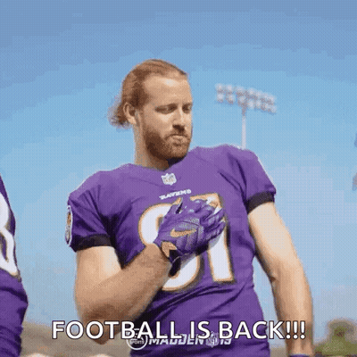 A Football Player Wearing A Purple Jersey And Gloves Is Standing On A Field And Says `` Football Is Back '' . GIF