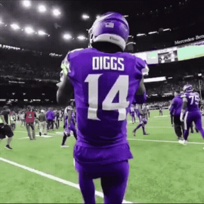A Football Player Wearing A Purple Jersey With The Number 14 On It Stands On A Field . GIF