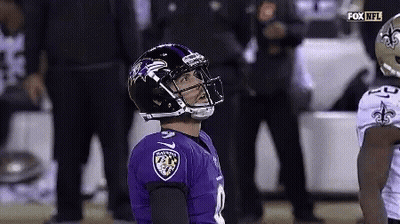 A Football Player Wearing A Ravens Jersey Looks Up At The Sky . GIF