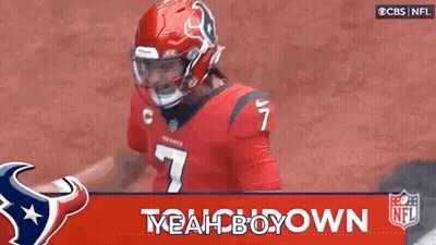 A Football Player Wearing A Red Helmet And A Red Jersey Is Standing In Front Of A Banner That Says Yeah Boy Down . GIF