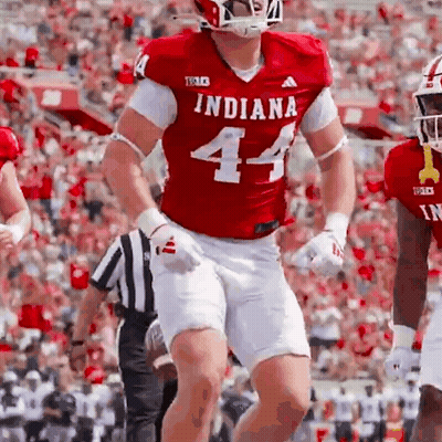 A Football Player Wearing A Red Indiana Jersey And White Shorts Is Running On The Field . GIF