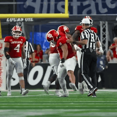 A Football Player Wearing A Red Indiana Jersey Is Being Tackled By Another Player GIF