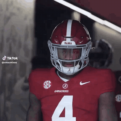 A Football Player Wearing A Red Jersey And A White Helmet Is Standing In A Locker Room . GIF