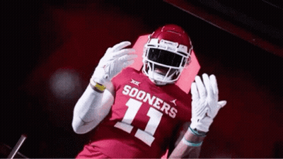 A Football Player Wearing A Red Jersey With The Number 11 On It Is Standing In A Tunnel . GIF