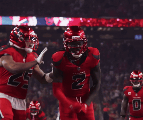 A Football Player Wearing A Red Jersey With The Number 2 On It Is Being Hugged By Another Player GIF