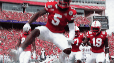 A Football Player Wearing A Red Jersey With The Number 5 Jumps In The Air GIF