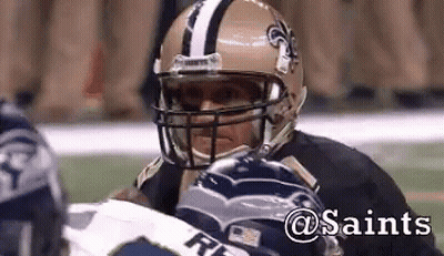 A Football Player Wearing A Saints Helmet Looks At Another Player GIF