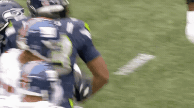 A Football Player Wearing A Seahawks Jersey Is Running With The Ball GIF