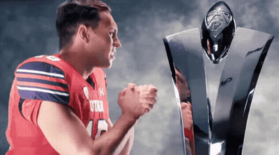 A Football Player Wearing A Utah Jersey Stands Next To A Trophy GIF