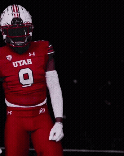A Football Player Wearing A Utah Uniform Is Pointing At Something GIF