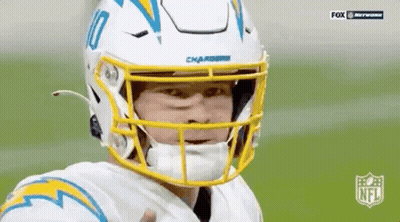A Football Player Wearing A White Helmet And A Yellow Visor Is Giving A Thumbs Up . GIF